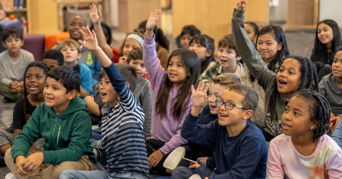 Generated placement image of elementary students raising their hands during an author visit.